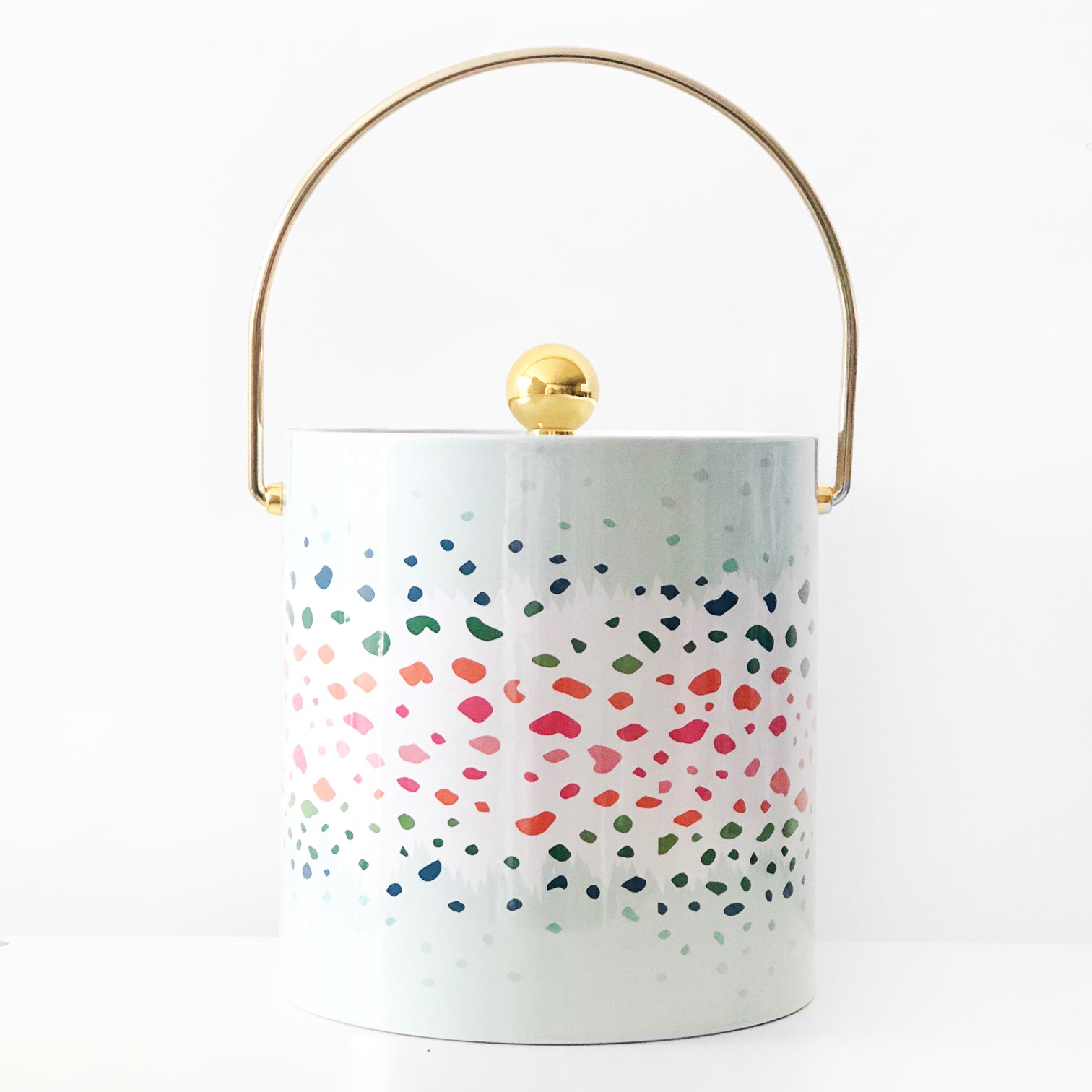 Introducing the Ice Bucket - Antelope Confetti, a chic addition to your entertaining collection. This white insulated ice bucket features a dazzling dotted design in pink, blue, and green shades, accented by a gold handle and lid—ideal for keeping wine cool at any event.