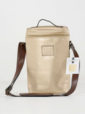 The Insulated 2-Bottle Wine Bag is a gold rectangular leather tote with a top handle, brown adjustable shoulder strap, front logo patch, and branded tag on the strap, displayed against a plain white background.
