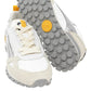 The Toronto Silver Splash Sneakers blend style and function, showcasing a chic design with white and beige tones, textured grey soles, and eye-catching orange accents. These lightweight hybrid sneakers provide optimal comfort and support, featuring distinctive white laces and side branding. Displayed in an upright position with one shoe slightly tilted, the circular grips on the sole are elegantly revealed.