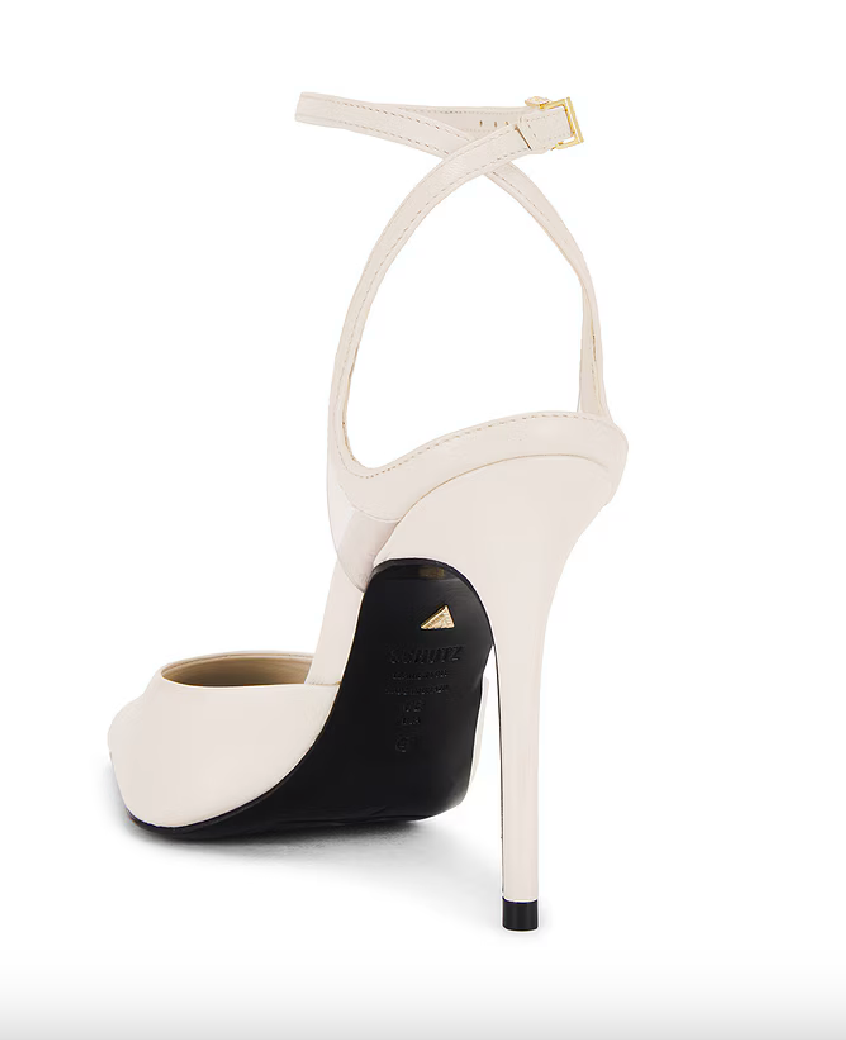 The Crawford Heel - Beige Lizzard is displayed from the back, showcasing its ankle strap with a buckle and a stiletto heel. This high-heeled shoe features a peep-toe design paired with a sleek black sole, effortlessly blending elegance and style.