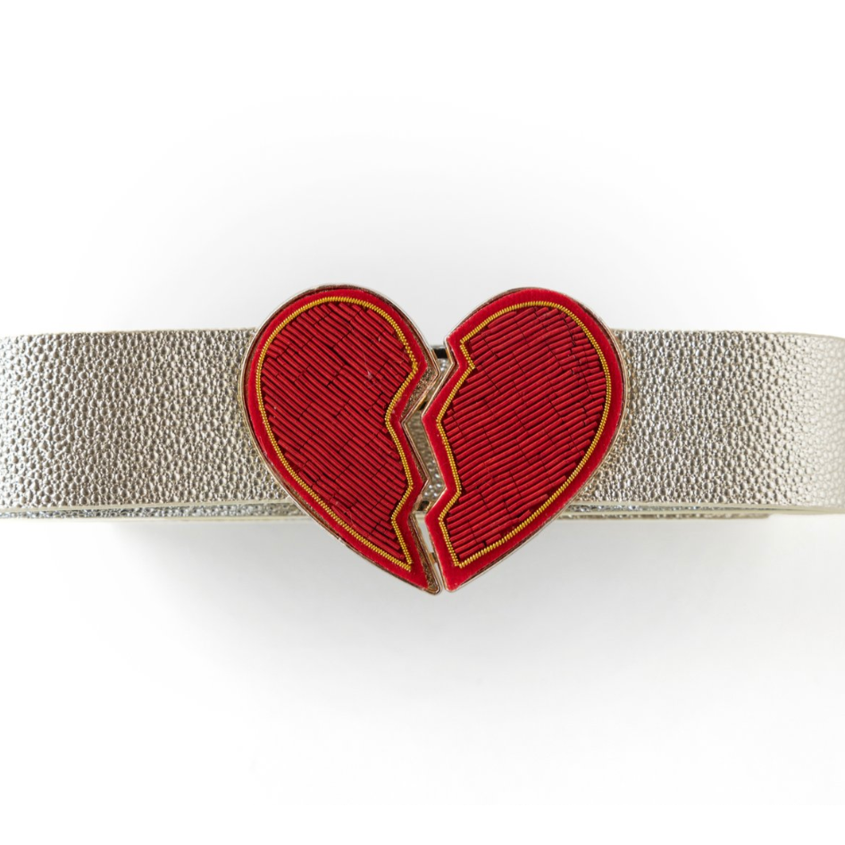 The Don't Go Breaking My Heart Belt - Red, with its textured silver design and eye-catching clasp featuring a red heart outlined in gold, makes the perfect heart-adorned accessory. Its distinctive split-heart motif effortlessly combines fashion with fandom, making it an ideal addition to your game day outfit.