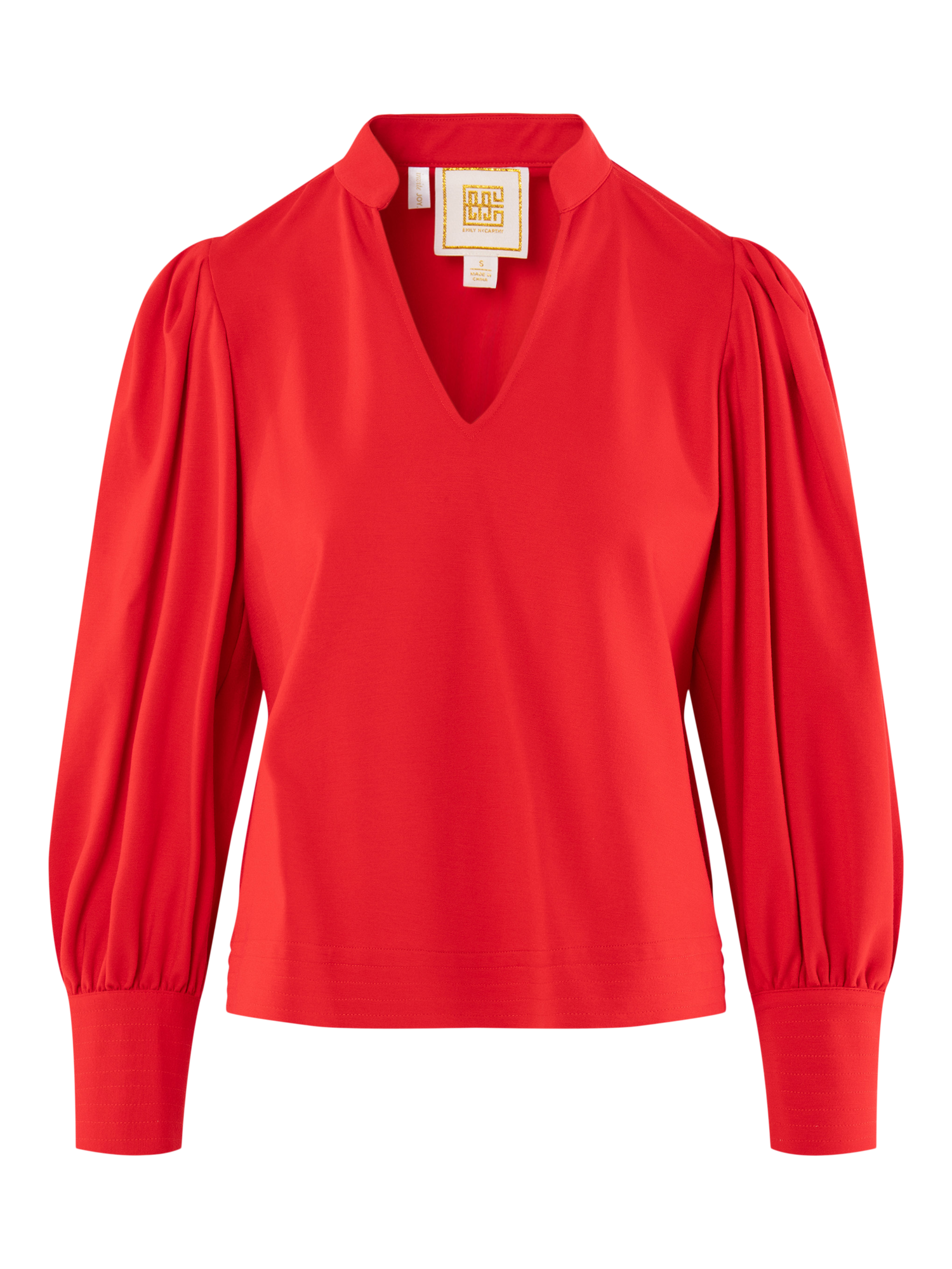The Hampton Top features a vibrant red hue, long sleeves, V-neck, gathered shoulders, wide buttoned cuffs, and a structured silhouette with a visible neck label for added detail.