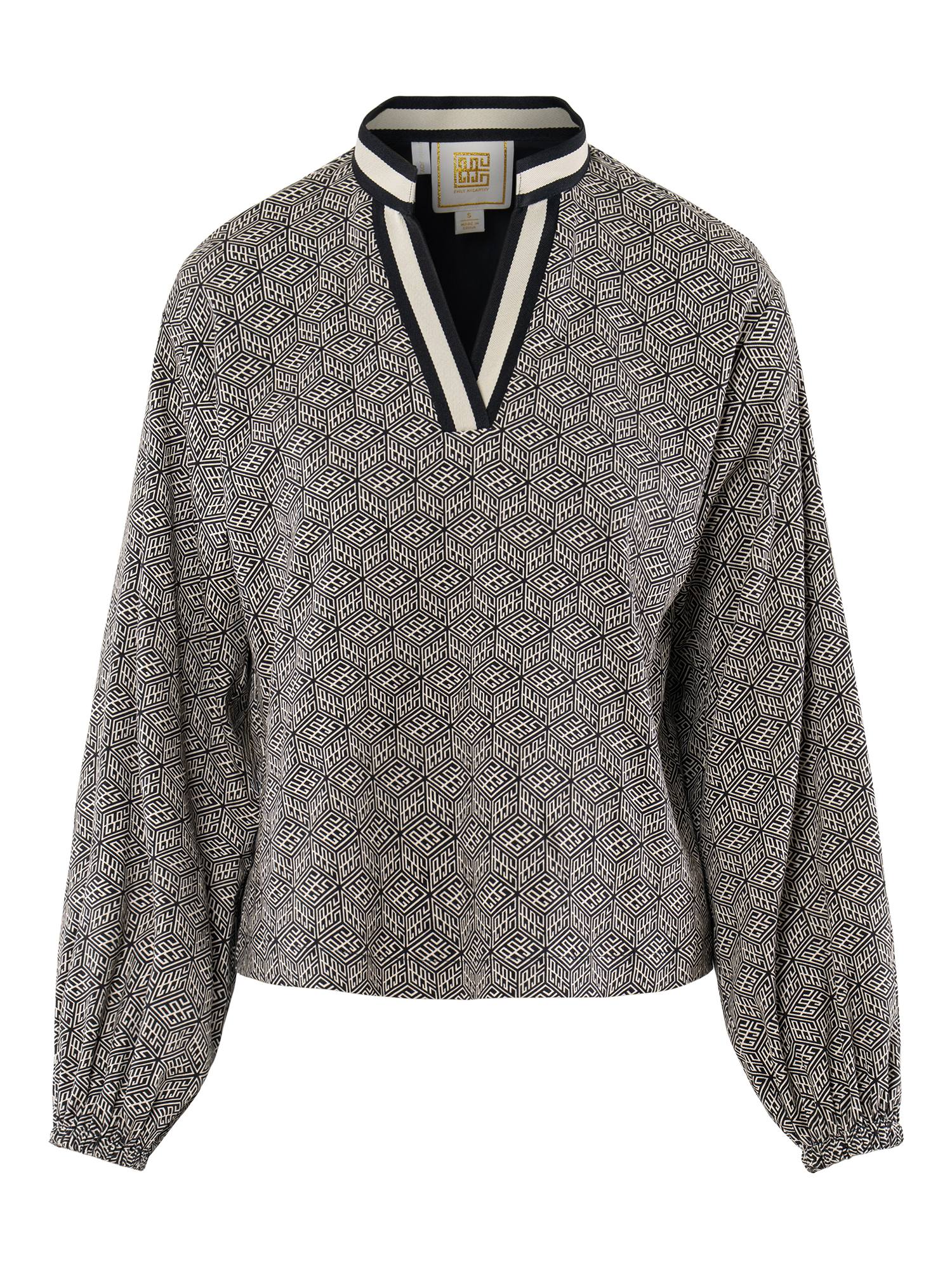 The Lolli Top boasts relaxed dolman sleeves, a geometric black-and-white print, V-neckline with matching trim, and elasticized cuffs, displayed on a white mannequin.