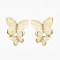 Explore our Papillon Earring - Gold, wearable art featuring intricately crafted butterflies, with a larger one elegantly perched on top and a smaller one beneath. These popular gold pieces stand out against a white background, blending sophistication with playful charm.