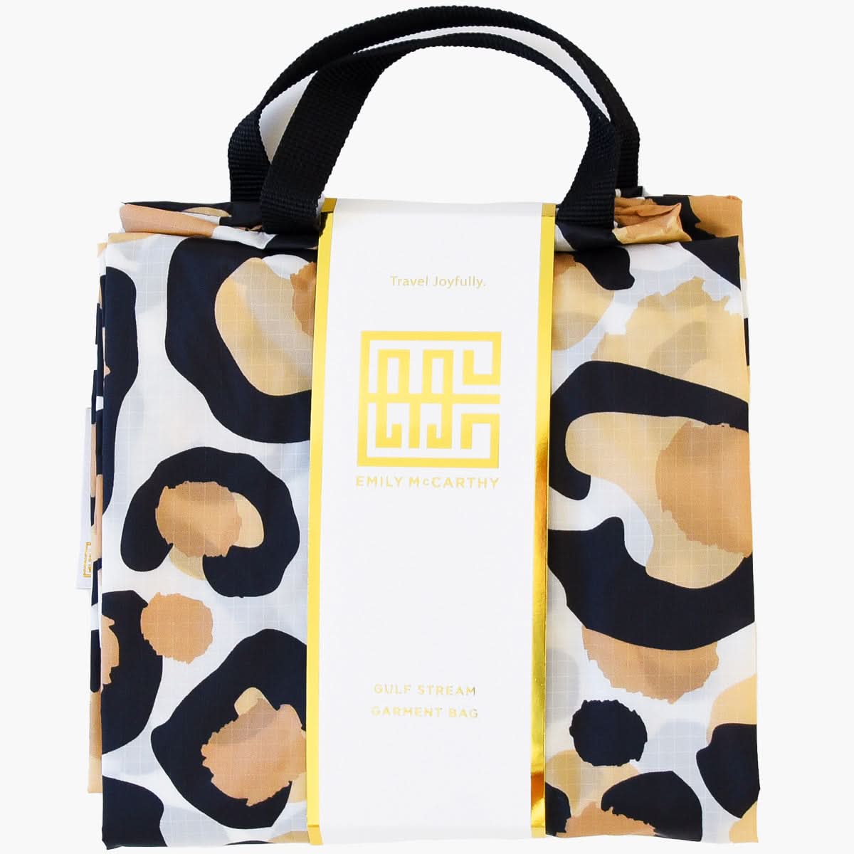 A folded travel garment bag featuring a black handle and a classic spot cheetah print in beige, black, and white. It includes a white label with a gold design that reads "Travel Joyfully." The Gulf Stream Garment Bag by Emily McCarthy is perfect for your adventures.