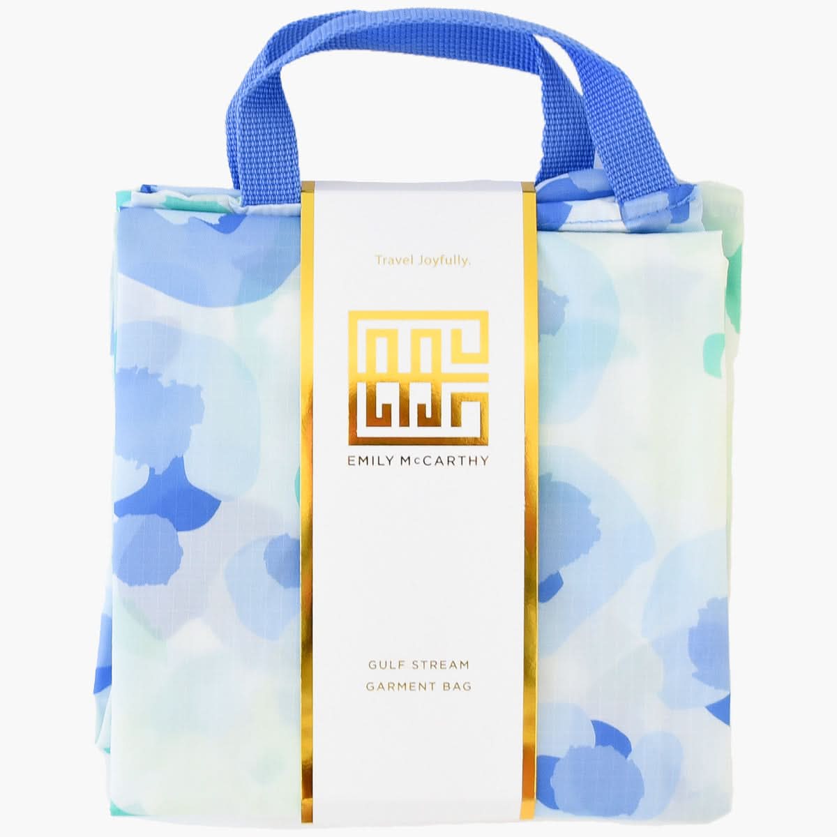 A folded travel garment bag featuring a blue floral pattern and a gold-trimmed label from the Emily McCarthy Collection. The label displays "Emily McCarthy" and "Gulf Stream Garment Bag - Seaglass Spot Cheetah" with the phrase "Travel Joyfully," complemented by sturdy blue handles.