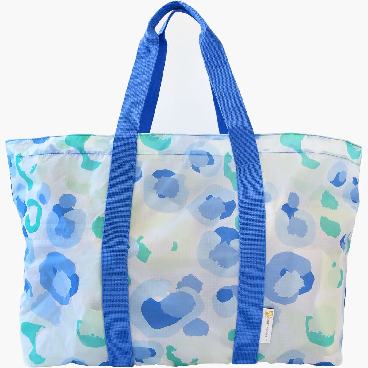 Introducing the Travel Tote - Seaglass Spot Cheetah by Emily McCarthy, showcasing a vibrant blue and green abstract bubble pattern. This stylish bag is equipped with two sturdy blue handles and a small rectangular label on one side, making it the perfect companion for your adventures.
