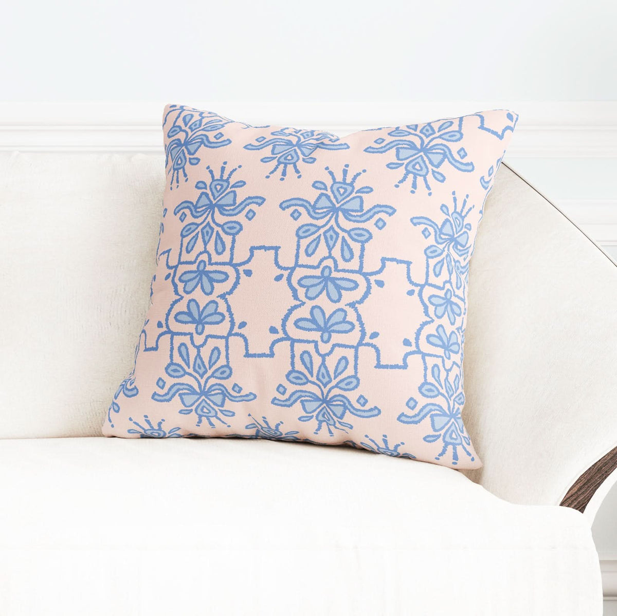 A cushion made from Fabric by the Yard - Bow Royalty, featuring a blue floral geometric hand-drawn pattern in beige tones on a cotton and linen blend, elegantly rests on a cream-colored sofa against a light wall.