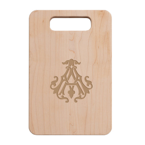 This handcrafted wooden cutting board, known as the 1-Letter Monogrammed Artisan Board, boasts an intricately carved monogram design featuring a single letter surrounded by decorative flourishes. Ideal as a personalized gift, it incorporates a handle at the top for easy transport.