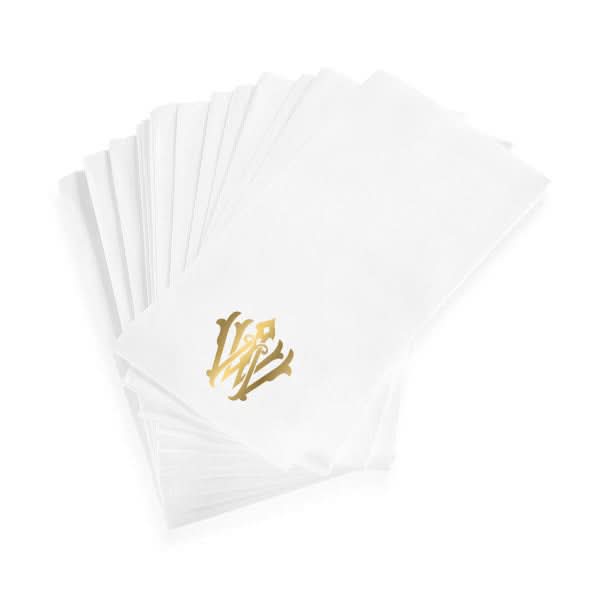 A stack of 1-Letter Monogrammed Guest Towels is fanned out, each white linen-textured towel displaying an elegant gold monogram in the lower center.