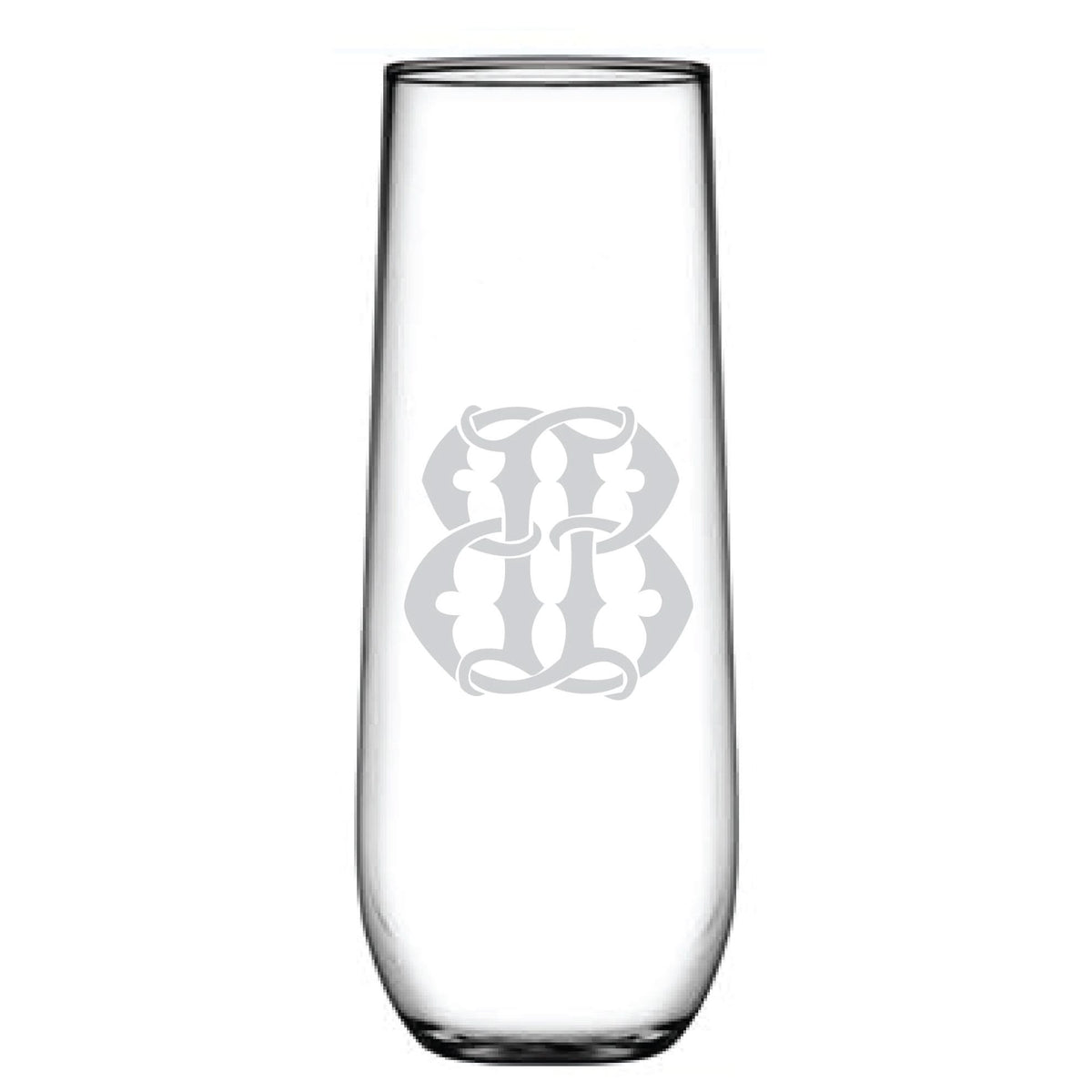 The tall, clear etched glass resembles a decorative monogram with its ornate, symmetrical design. Named the 1-Letter Monogrammed Stemless Champagne Flute, it stands elegantly empty against a white background.
