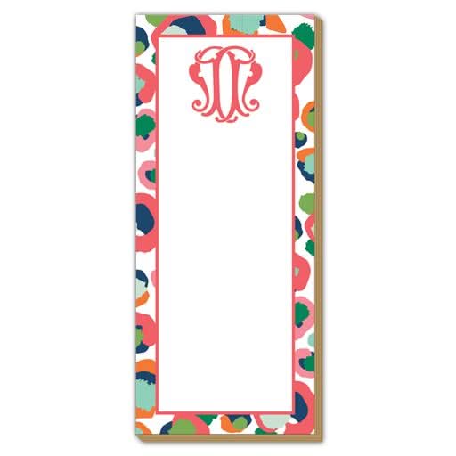 The Gift Bar - Luxe Skinny Pad is a rectangular notepad made from durable 100# card stock, adorned with a vibrant abstract border featuring splashes of orange, blue, and green. It has a red monogram design at the top center and measures 3.5 x 8.5 inches. Its blank white interior makes it ideal for jotting down your thoughts.