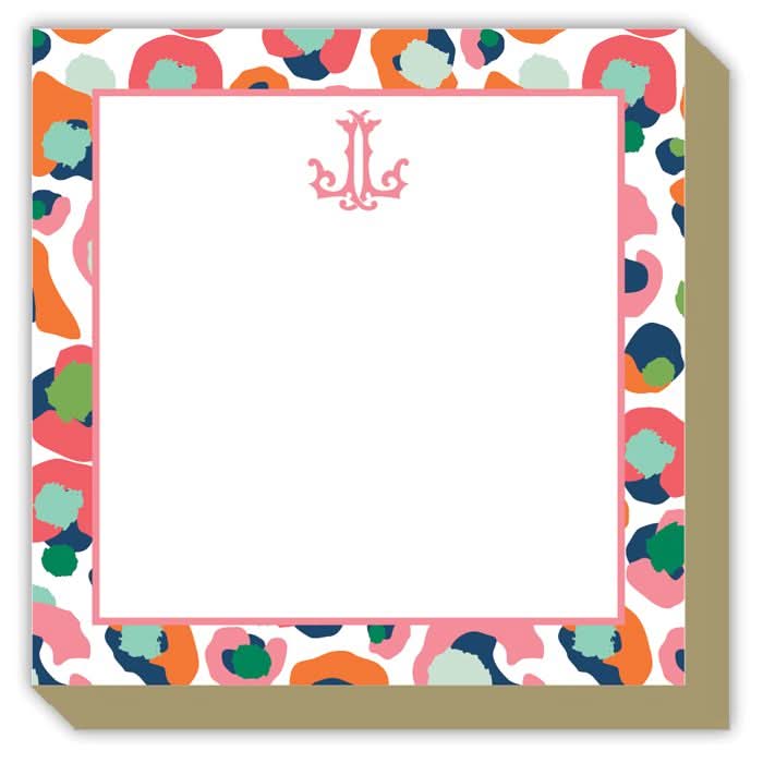 The Gift Bar - Mini Luxe Notepad, measuring 4 x 4 inches, boasts colorful abstract patterns in pink, blue, and green around the border. It features a decorative monogram at the top with a stylized letter J and includes 100 sheets ideal for jotting down notes.