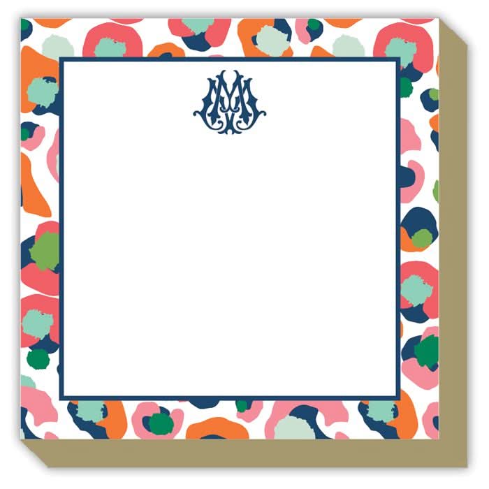 The Gift Bar - Mini Luxe Notepad, sized at 4 x 4 inches, boasts a decorative border filled with colorful abstract shapes in shades of blue, red, green, and orange. Its blank center is adorned with ornate blue initials at the top. This delightful notepad includes 100 sheets and sits gracefully against a beige background.