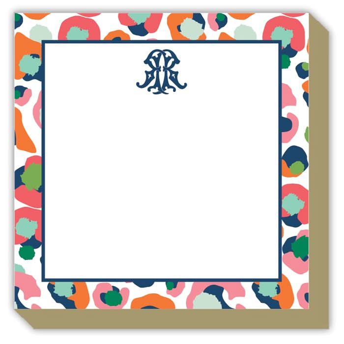 The Gift Bar - Luxe Notepad is a 5.5 x 5.5 notepad featuring a colorful abstract border with red, orange, green, and blue spots. It includes a decorative monogram at the top center and offers 65 sheets for writing.