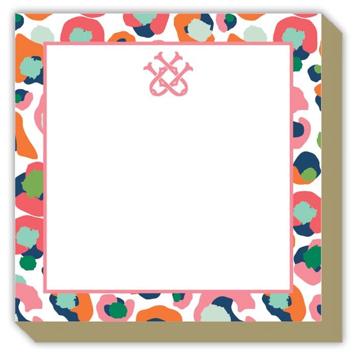 The Gift Bar - Mini Luxe Notepad showcases a vibrant design with abstract, multicolored blobs framing a spacious white square. A stylized pink ampersand symbol is prominently centered at the top. This 4 x 4-inch notepad contains 100 sheets and features an edge with a subtle shadow that creates an engaging 3D effect.