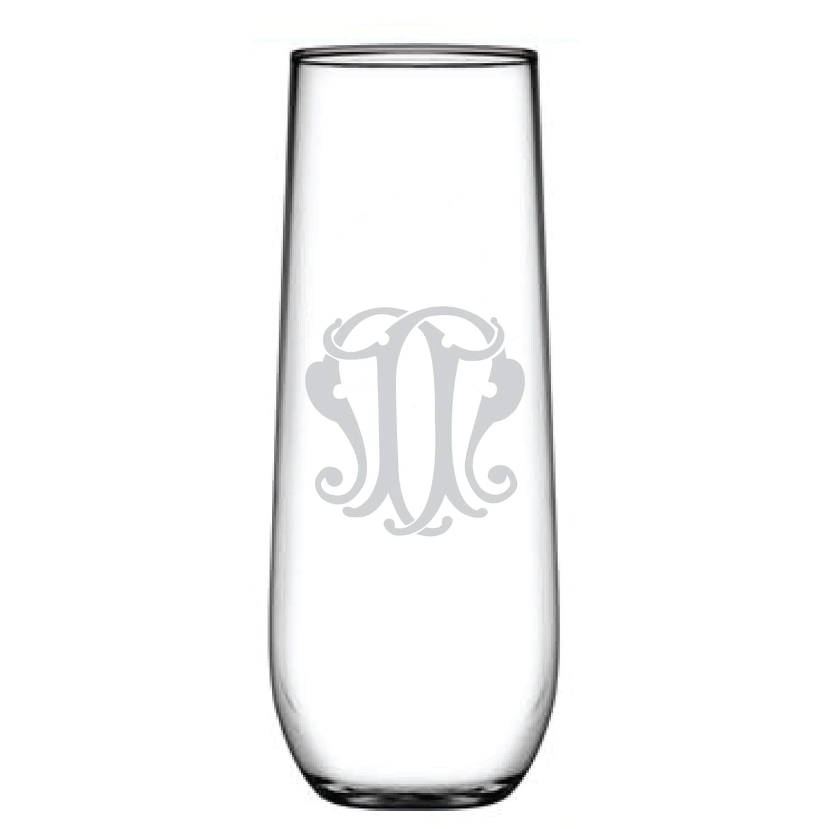 A tall, clear stemless champagne flute featuring an ornate monogram etched in the center offers a personalized, elegant touch.